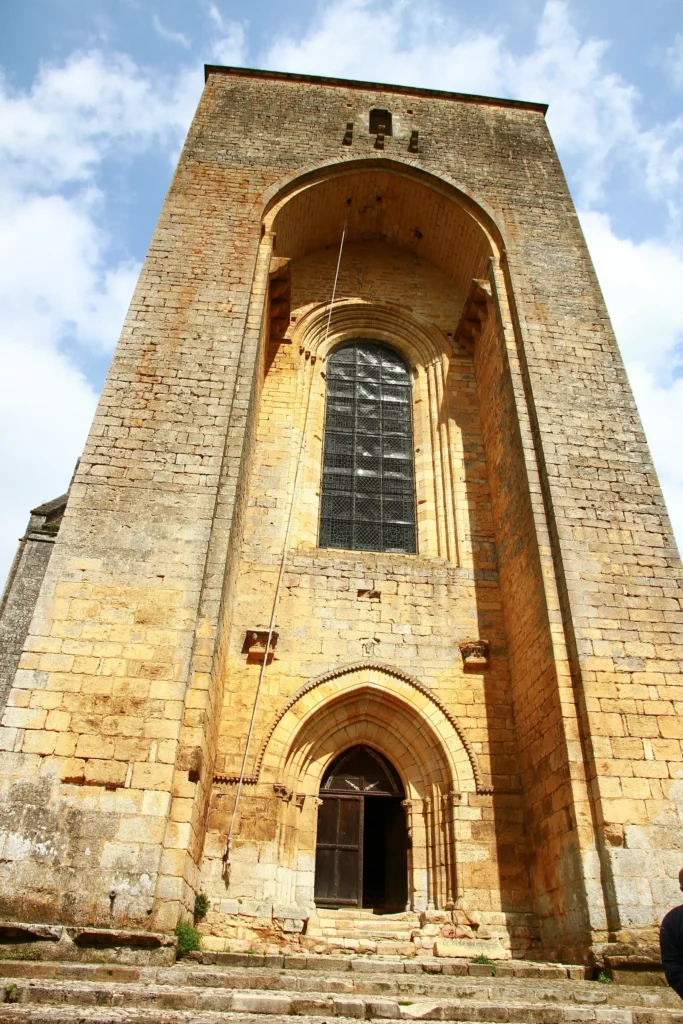 Abbaye de Saint-Amand-de-Coly — la façade-donjon et son grand arc brisé en pierre dorée