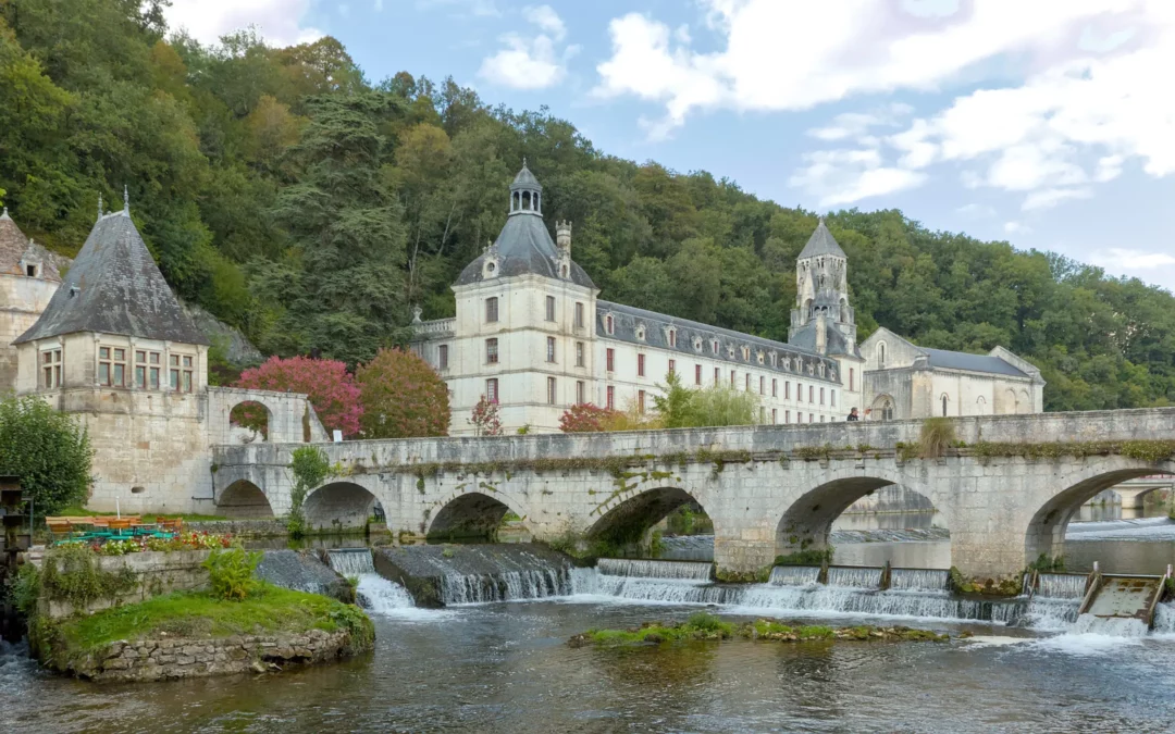 Brantôme — La Dronne, le pont coudé et l'abbaye au pied du coteau boisé.