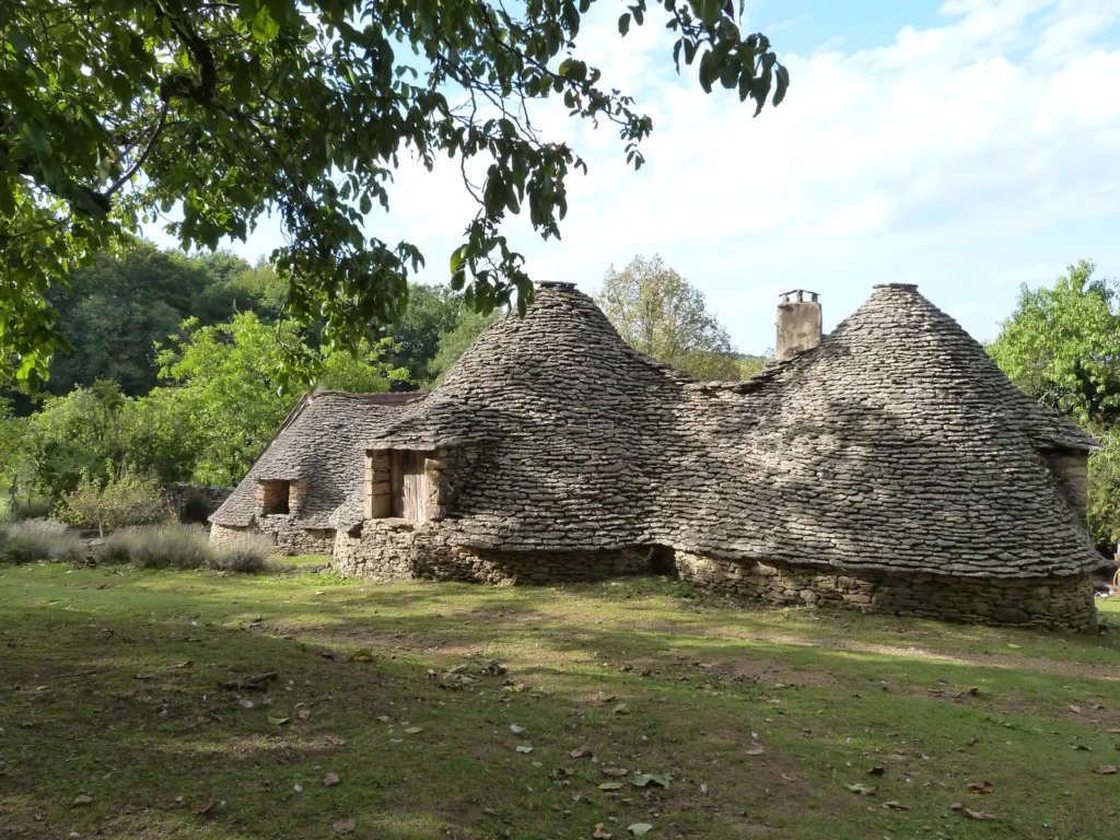 Cabanes du Breuil — Groupe de cabanes accolées sous les arbres, toits de lauzes coniques.