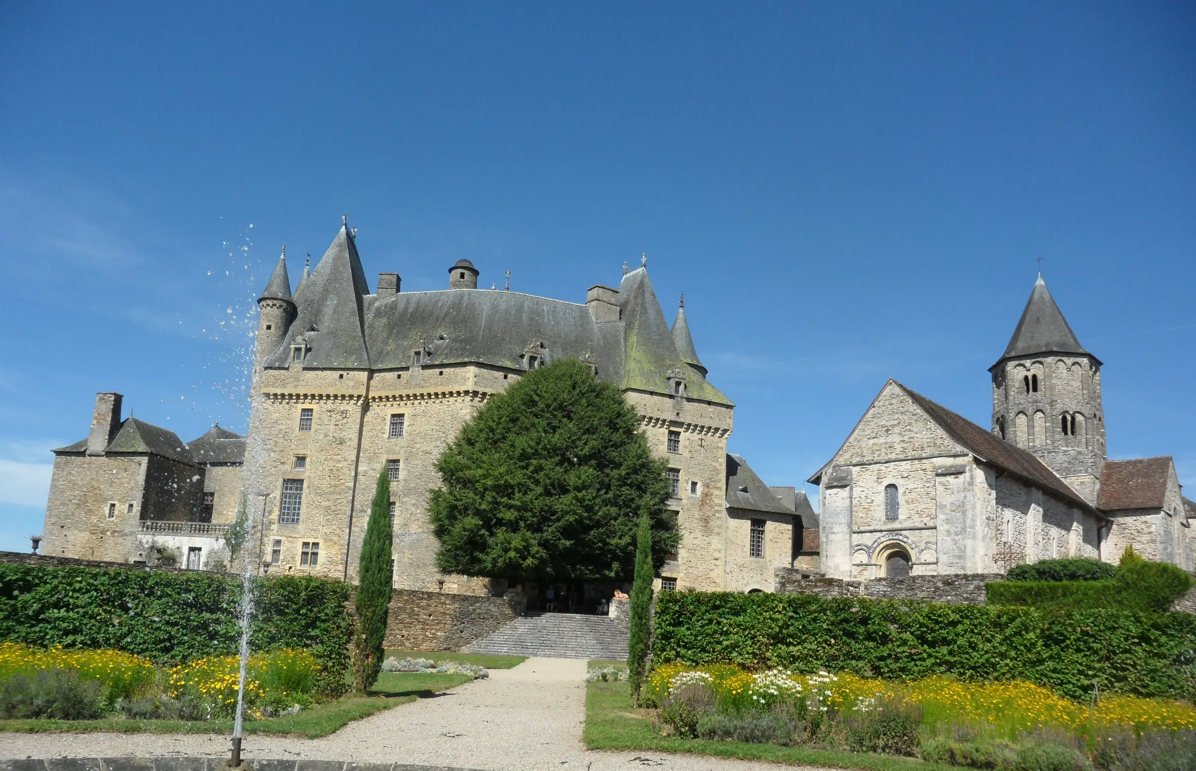 Jumilhac-le-Grand — le château aux toits hérissés et l'église romane vus depuis les jardins