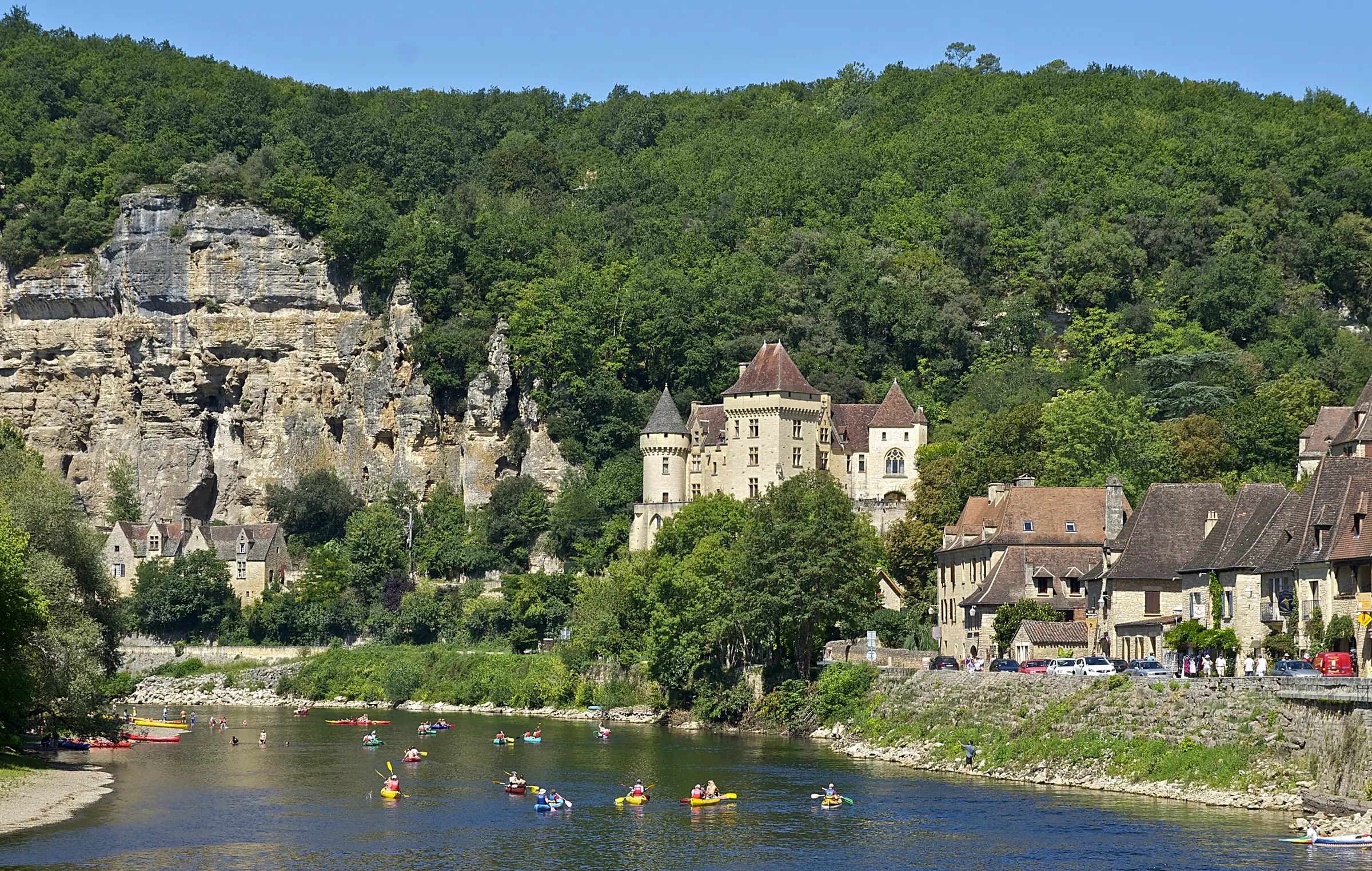 La Roque-Gageac — La falaise, le manoir de la Malartrie et les maisons du village au bord de la Dordogne, canoës sur l'e