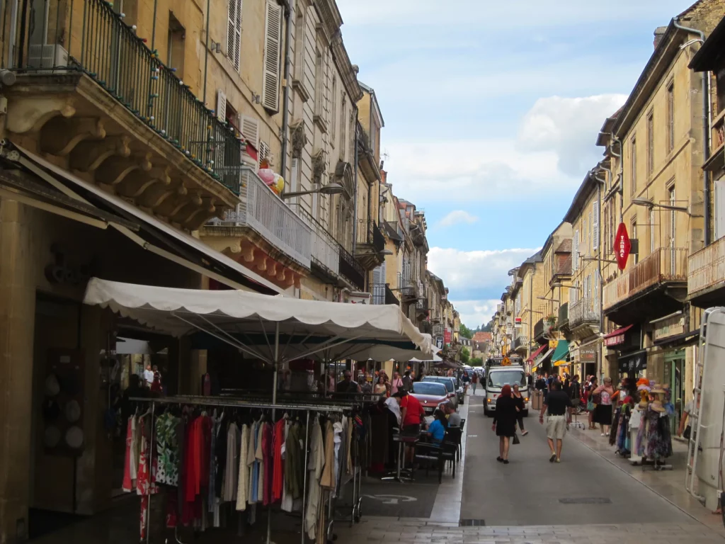 Rue commerçante de Sarlat un jour de marché, étals sous les auvents