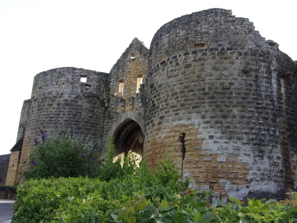Porte des Tours de Domme — porte des Tours vue de biais, massifs fleuris au pied