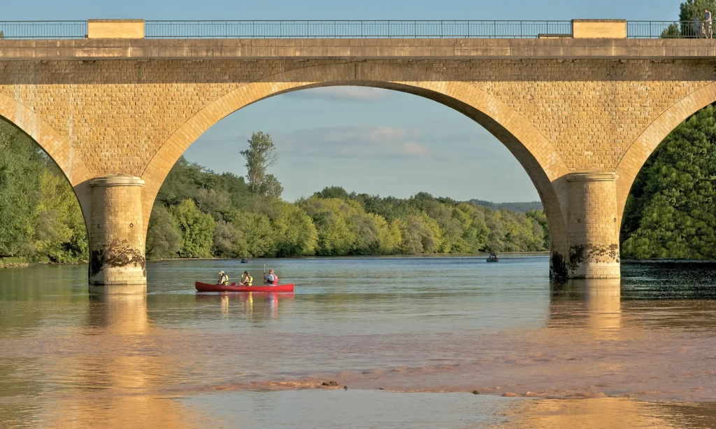 Canoë sous le pont de pierre de Limeuil, sur la Dordogne, en fin d'après-midi d'été