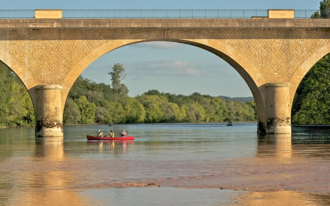 Canoë sous le pont de pierre de Limeuil, sur la Dordogne, en fin d'après-midi d'été