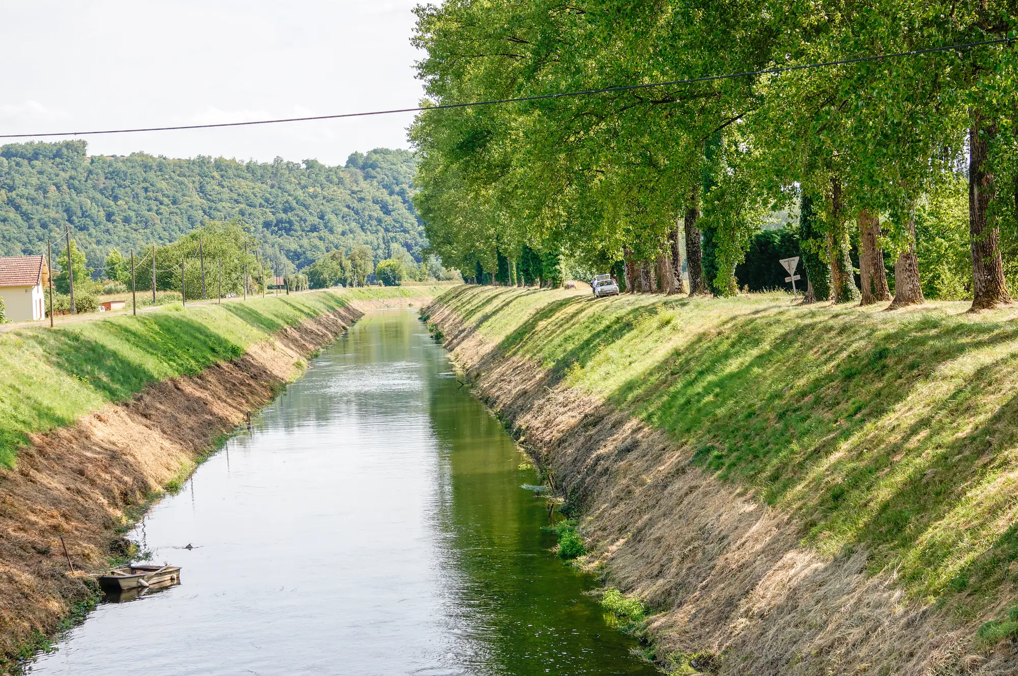 Le canal de Lalinde à Mauzac, entre ses berges herbeuses et une allée d'arbres, au début de son parcours