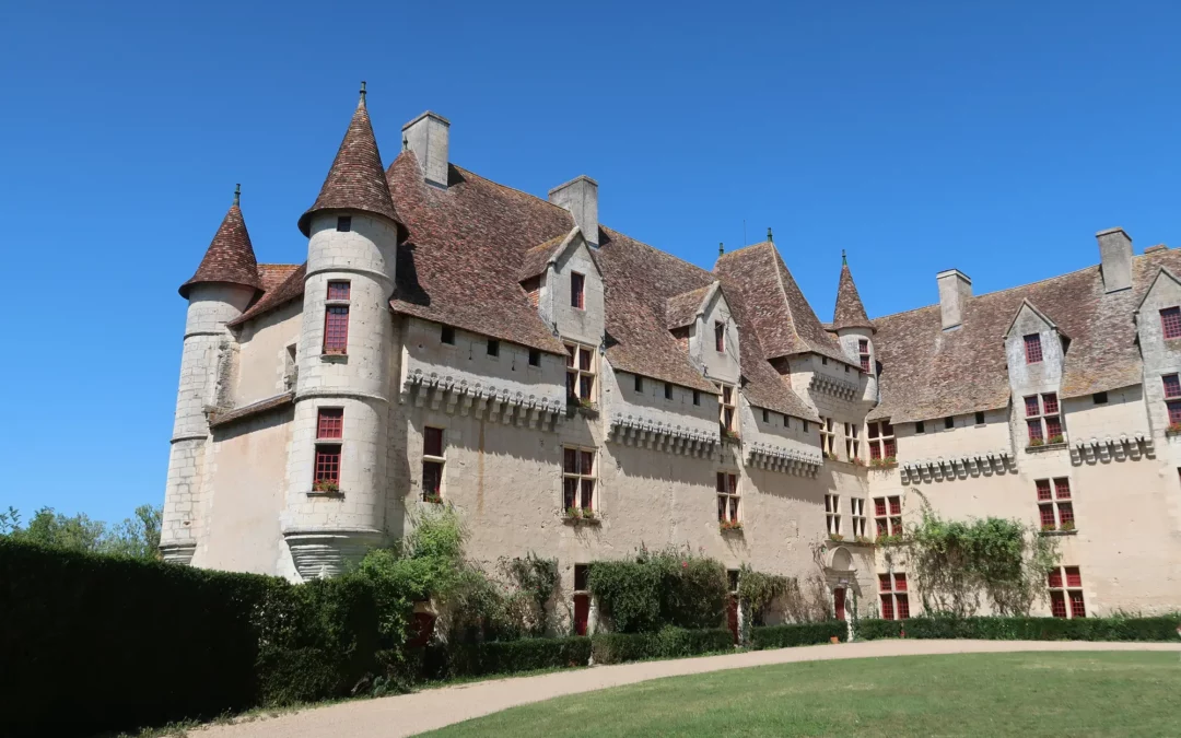 Le château de Neuvic, ses tours coiffées de tuiles et sa longue façade Renaissance, au-dessus d'une pelouse