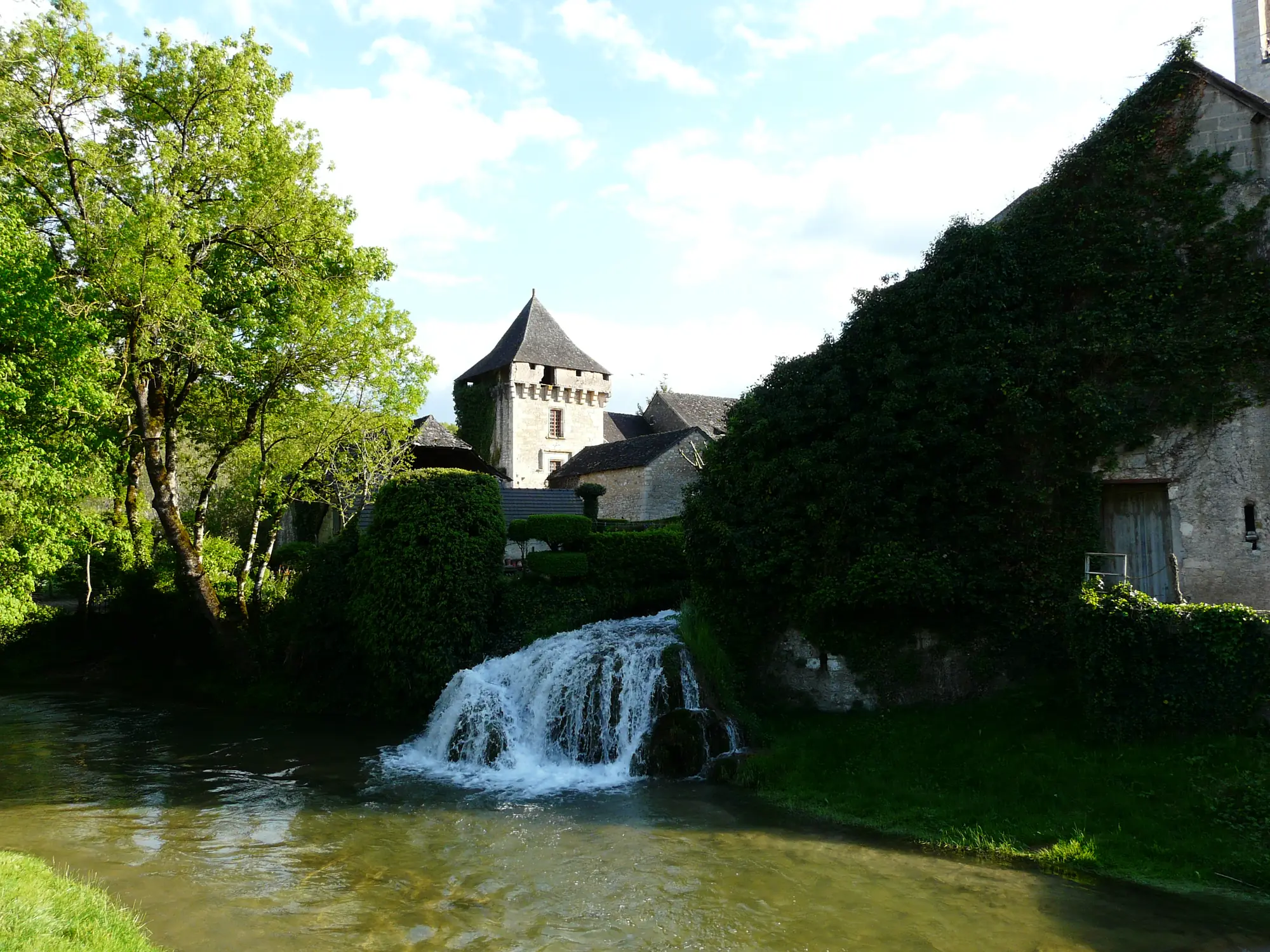Une cascade du Coly à Condat-sur-Vézère, avec le donjon de la commanderie à l'arrière-plan