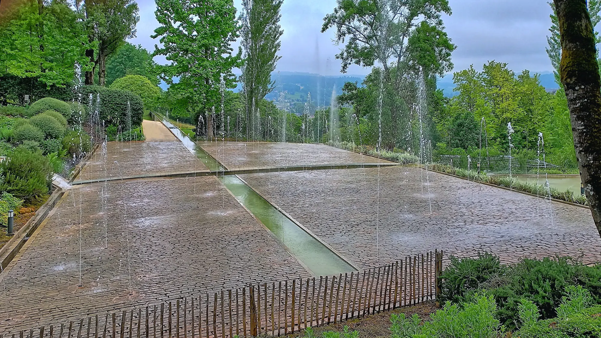 Le jardin d'eau des Jardins de l'Imaginaire, ses jets et son canal, au-dessus de la vallée de la Vézère