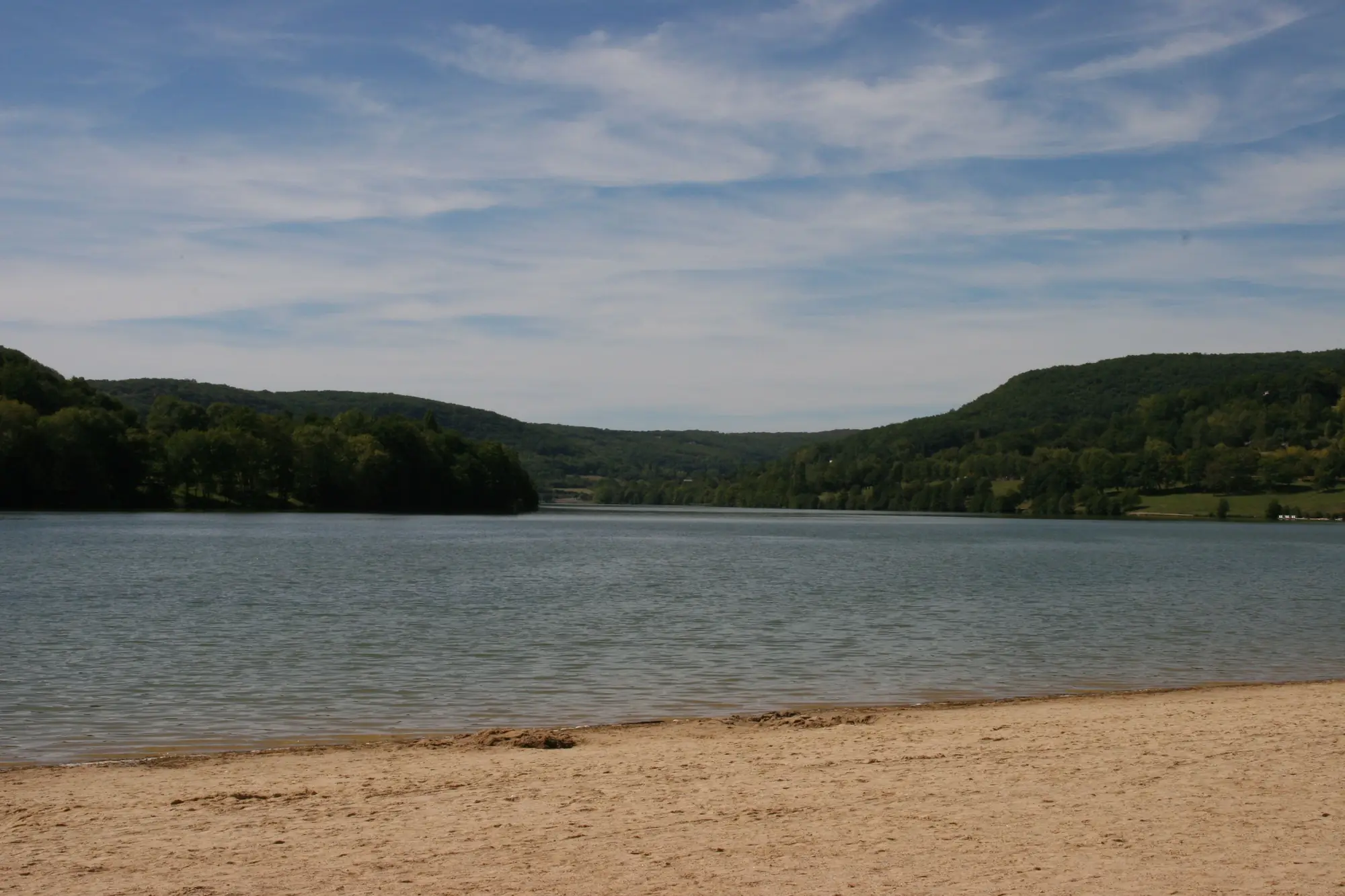 La plage de sable du lac du Causse, en Corrèze, et ses collines boisées