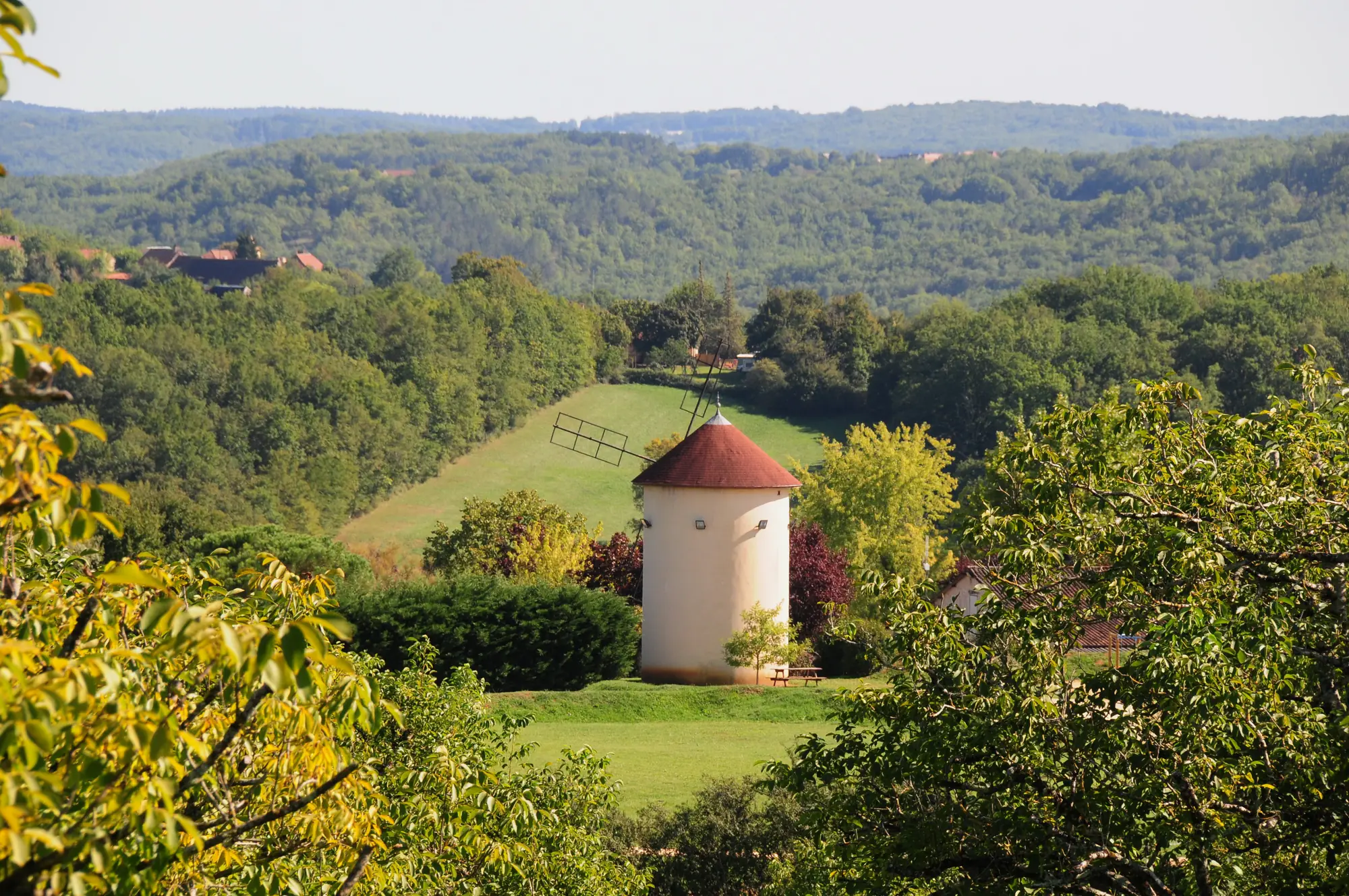 Une tour de moulin à vent coiffée de rouge, dans les collines de Saint-Martial-de-Nabirat